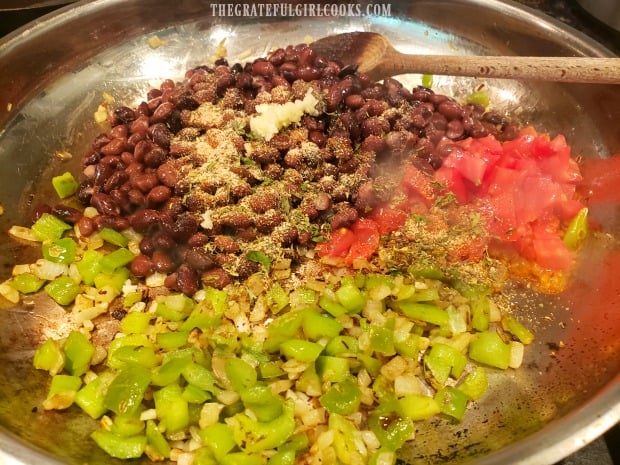 Green peppers, tomatoes, black beans and spices are added to the skillet to cook.