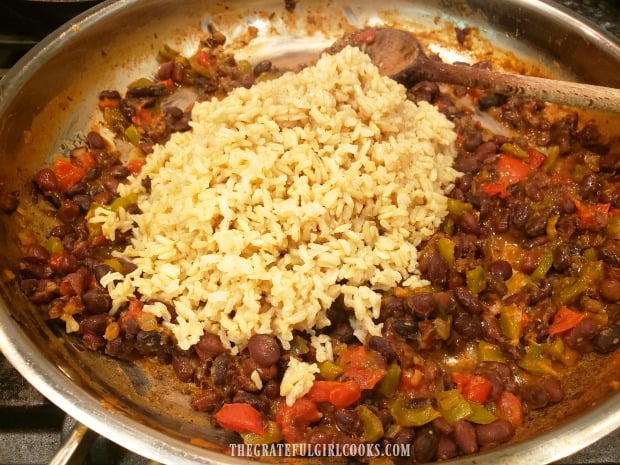 Cooked brown rice is added to the skillet, and stirred in, to combine.