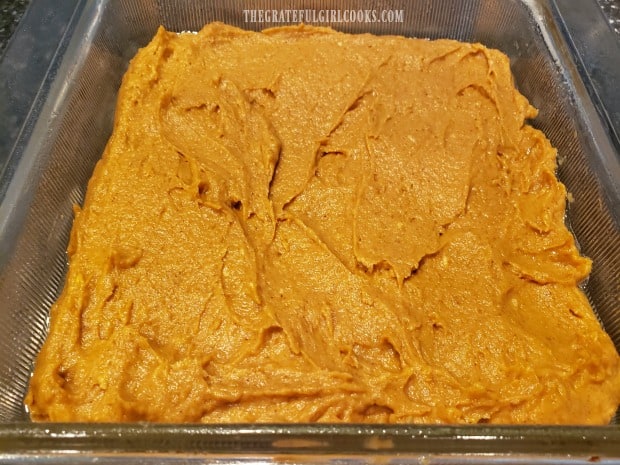 Batter for frosted pumpkin bars is spread in a greased 8x8" pan for baking.