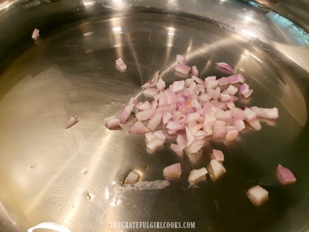 Chopped shallots are cooked in hot olive oil in a large skillet.