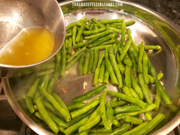 Green beans and vegetable (or chicken) broth are added to the skillet.