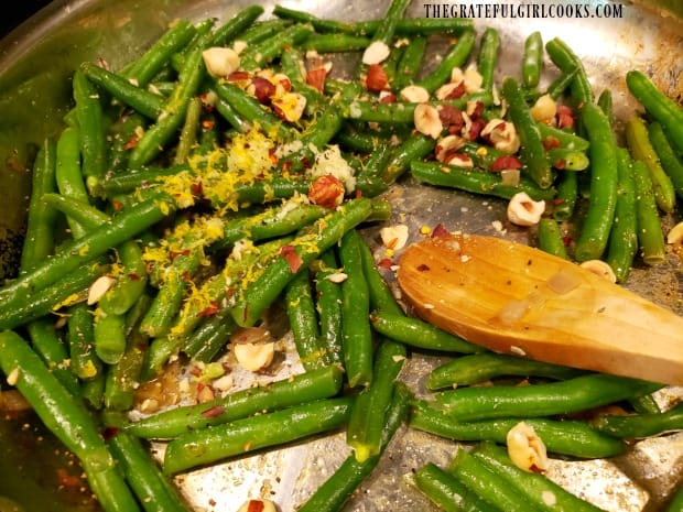 Minced garlic, chili flakes, lemon zest and hazelnuts are added to green beans.