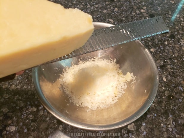 Finely grating Parmesan cheese to add to the cooked orzo, once done.