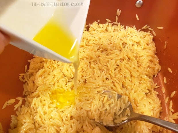 Melted butter is added to the cooked orzo.