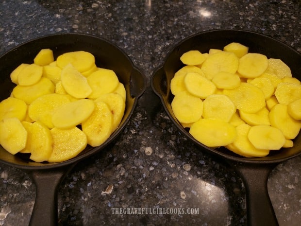 Peeled, thinly sliced potatoes are fanned out in baking skillets or pans.