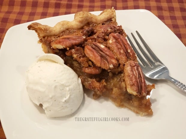 A slice of awesome pecan pie, with a scoop of ice cream on the side.