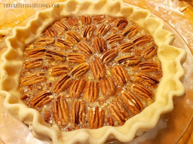 Pecans decorate the top of the pie before it is baked.