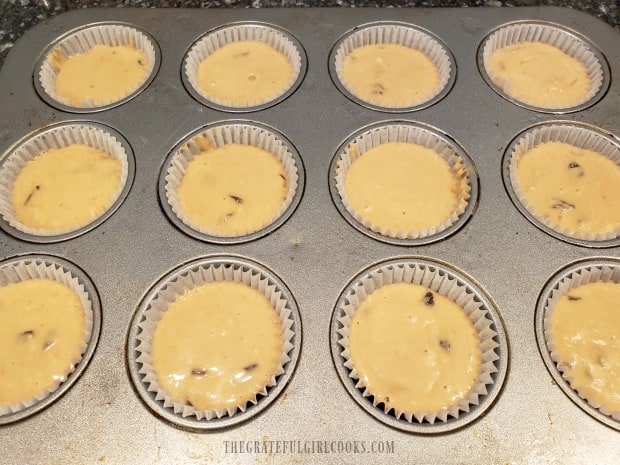 Paper-lined muffin cups are filled with the muffin batter.