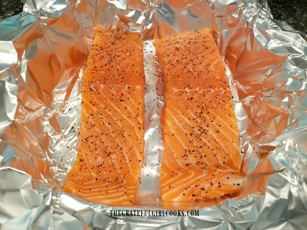 Skinless salmon fillets are lightly seasoned with salt and pepper.