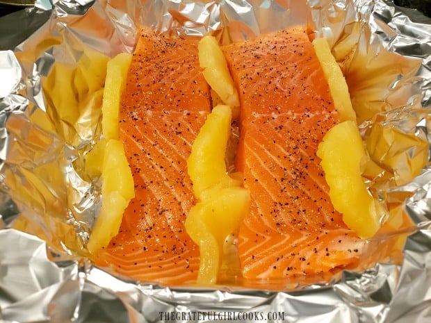 Pineapple rings (cut in half) are wedged around the salmon fillets in pan.