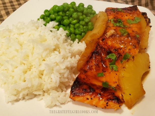 Sweet Spicy Salmon, served on a white plate with steamed rice and green peas.