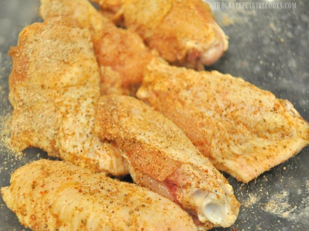 Chicken wings are covered with spices before cooking.