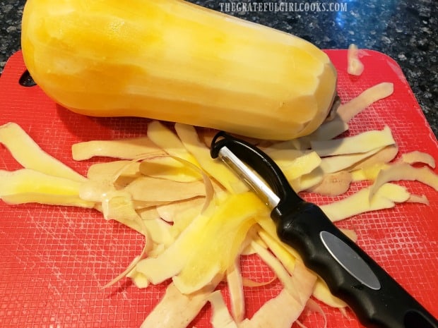 A vegetable peeler is used to peel the butternut squash.