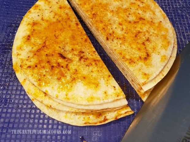 A stack of seasoned tortillas is cut in half.