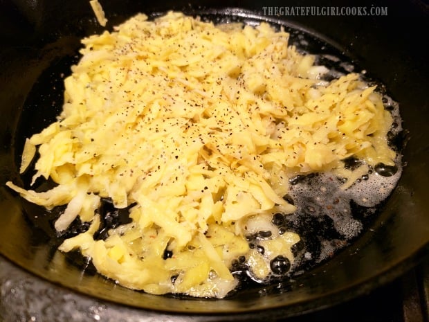 The hash browns are placed in hot skillet and seasoned.
