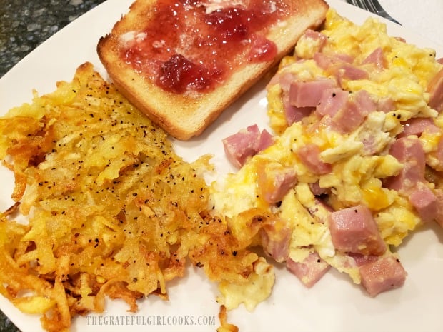 Crispy homemade hash browns, served with scrambled eggs, ham, and toast.