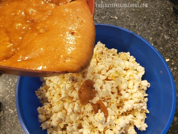 Pouring the hot caramel sauce over the popcorn in large bowl.