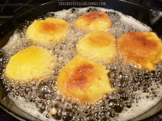Hush puppies are carefully turned to fry the other side in the hot oil.
