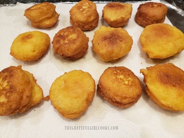 Paper towels absorb oil from the fried hush puppies before serving.