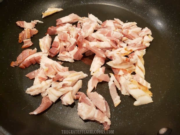 Chopped bacon is quickly fried until crispy in a skillet.