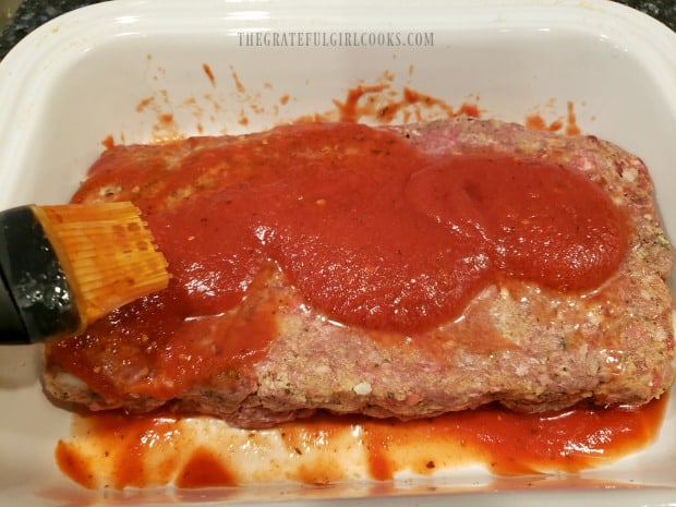 Meatloaf is covered with marinara sauce before baking.