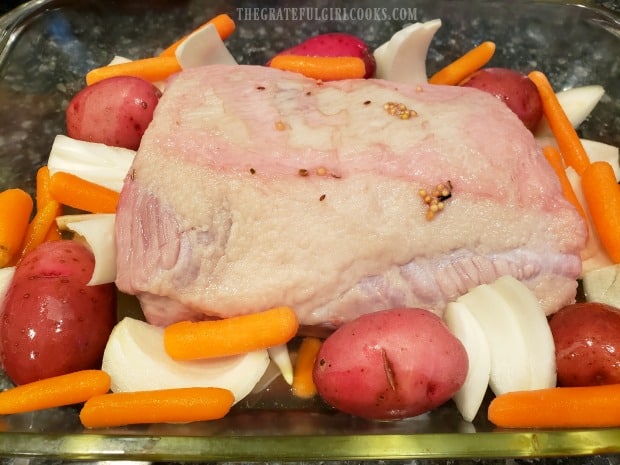 Red potatoes, baby carrots and onion wedges are place around the corned beef.