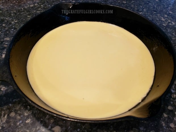 Batter is poured into a hot, buttered skillet before baking.