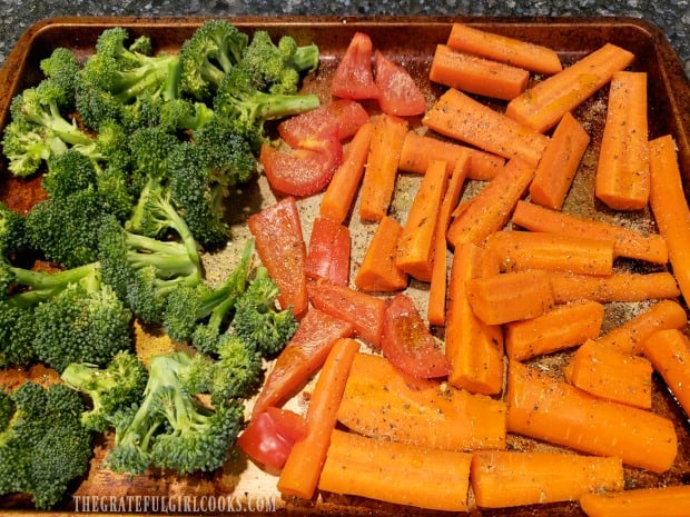 Italian spice mixture is sprinkled over olive oil-drizzled veggies on baking sheet.