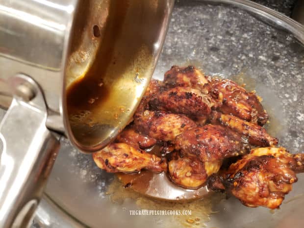 Asian BBQ chicken wings are coated and tossed in sauce before serving.