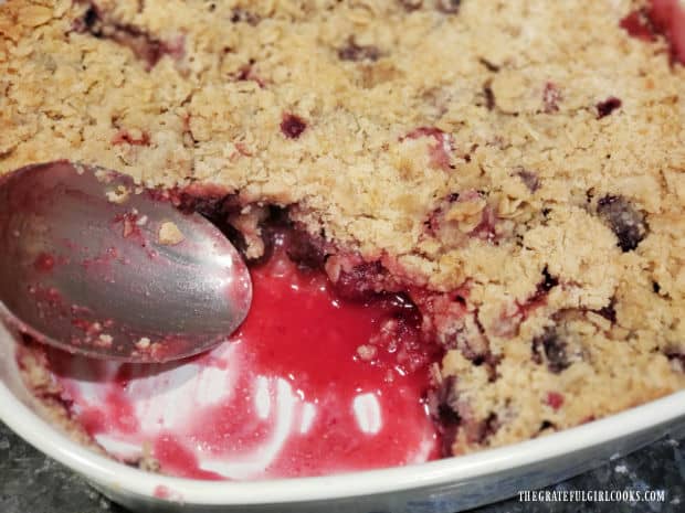 A spoonful of fruit crisp has been removed, revealing the inside of the dessert.