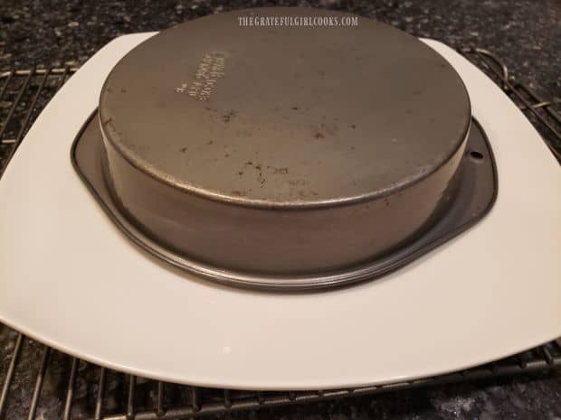 The cake is inverted onto a serving platter, and then the cake pan is removed.