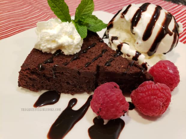 Whipped cream, chocolate syrup and mint leaf garnish the top of the flourless chocolate cake.