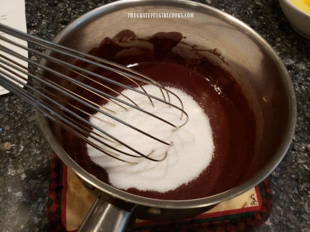 Granulated sugar is whisked into melted butter and chocolate mixture.