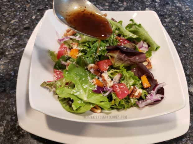 The vinaigrette is drizzled onto a mixed green salad.