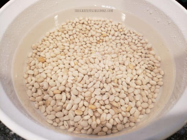 Dried navy beans are soaked in water for hours to soften them.