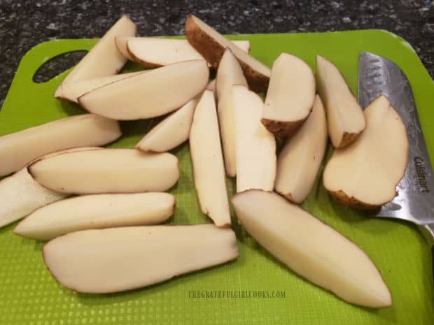 Unpeeled potatoes are sliced into wedges before baking.