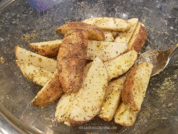 Seasoning mix is tossed with the potato wedges to coat them in spices.