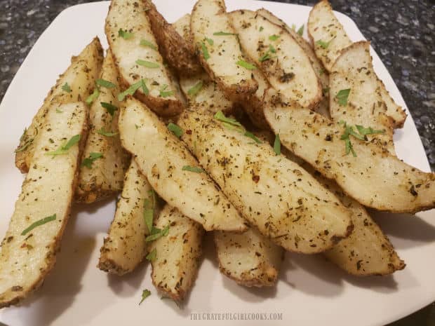 Parmesan garlic potato wedges are garnished with cilantro or parsley before serving.