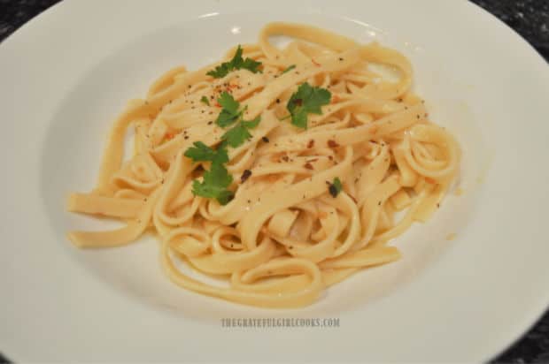 Pasta in wine and garlic sauce is served, garnished with Parmesan cheese and parsley.