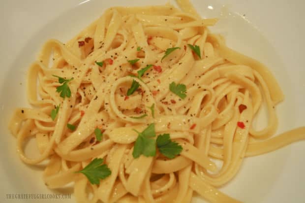 Close up photo of pasta in wine and garlic sauce, served in a white bowl.