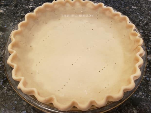 A 9-inch unbaked deep dish pie shell is pricked with a fork before adding ingredients.