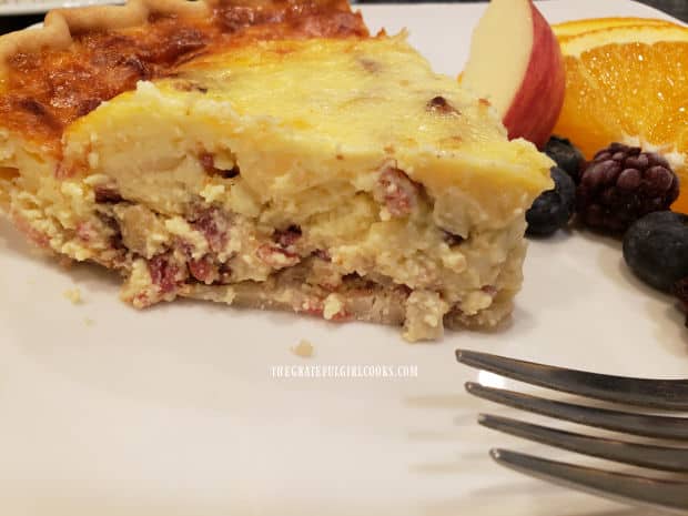 A slice of Quiche Lorraine, with fresh fruit on the side.