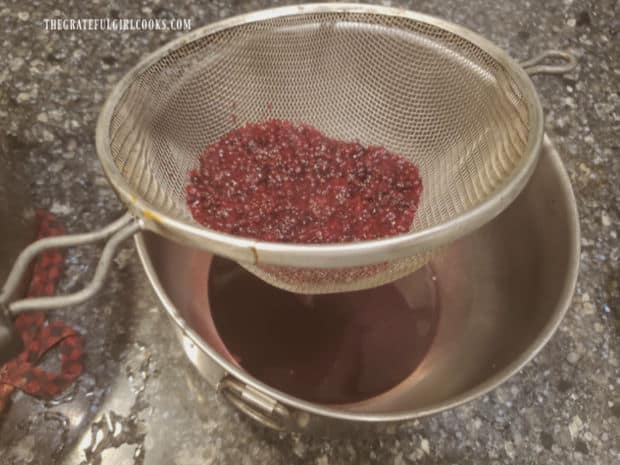 Pressing cooked blackberries through sieve to remove seeds from syrup below.