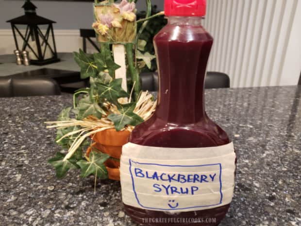 A bottle full of homemade blackberry pancake syrup is ready to use.
