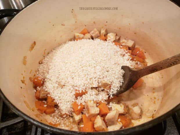Arborio rice and cooked chicken pieces are added to the butternut squash in pan.