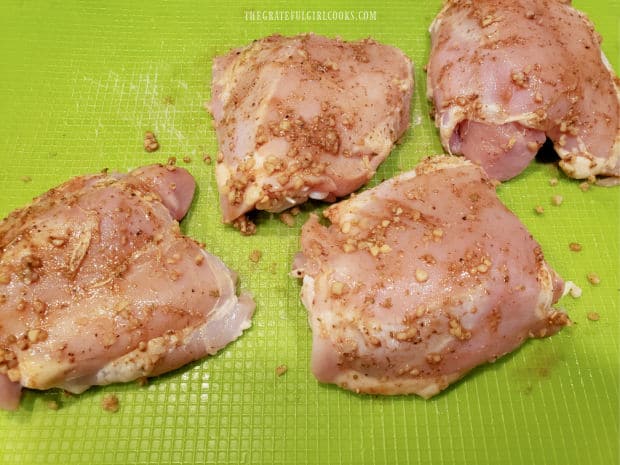 Four bone-in, skinless chicken thighs are coated with spice mix before cooking.