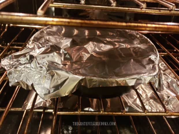 Garlic lime chicken thighs are baked in a covered skillet in oven.