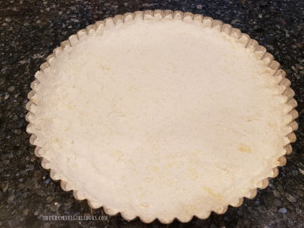 Crust mixture is firmly pressed into the tart pan to form a solid base and sides.