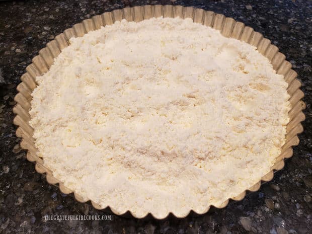 Crumbly crust mixture is poured into a tart pan (with a removable bottom).