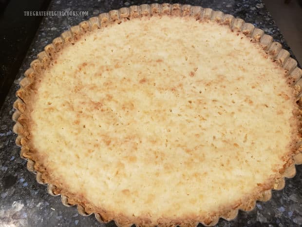 After baking, the crust for the lemon cream cheese tart is golden brown.